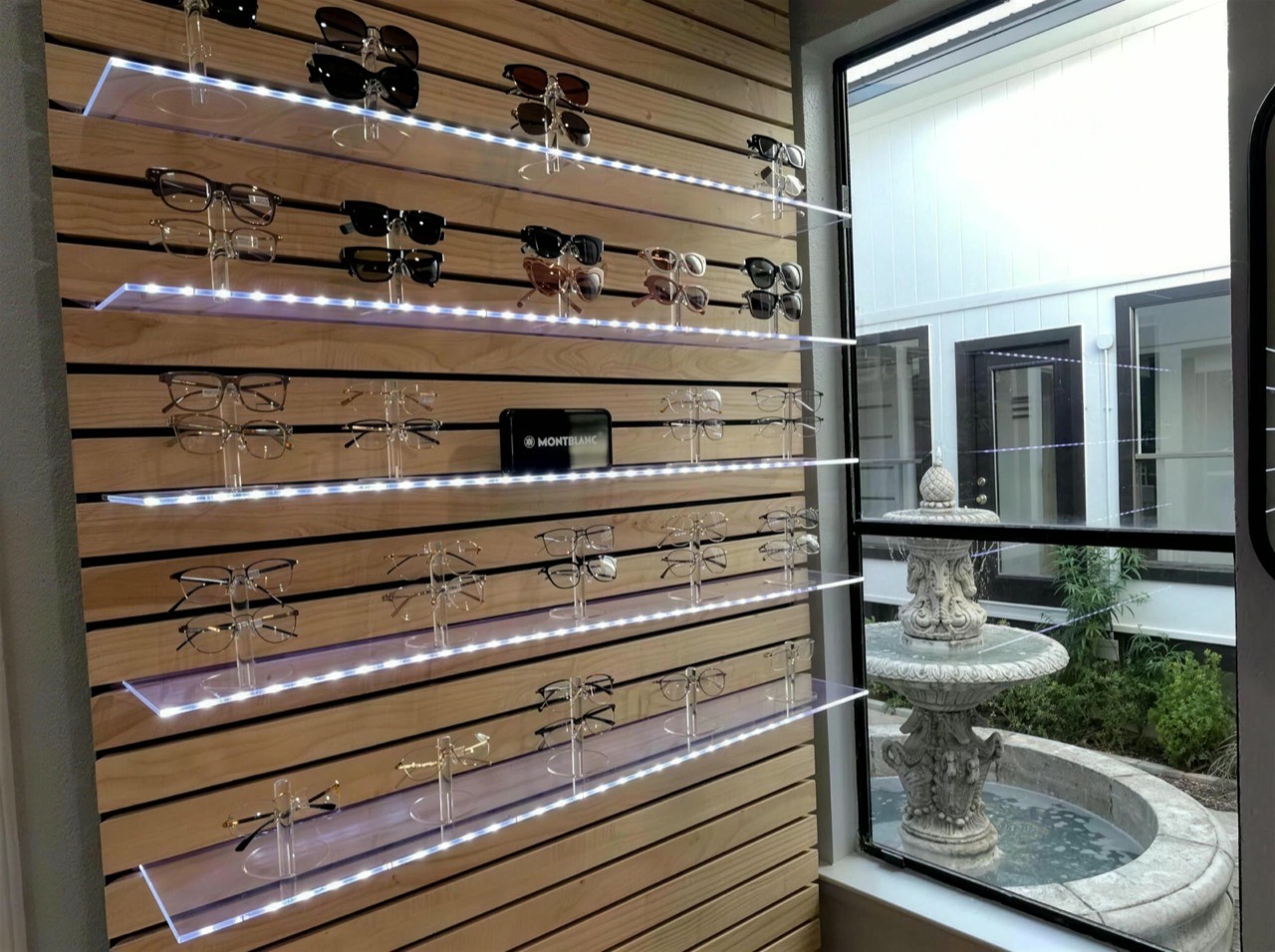 Backlit designer eyewear wall at Aura Eye Center with courtyard fountain view